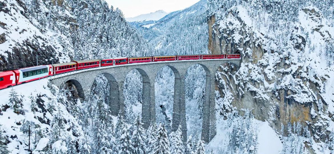 1 the-glacier-express-train-on-viaduct-nearby-snowy-mountain-woods-swiss-alps